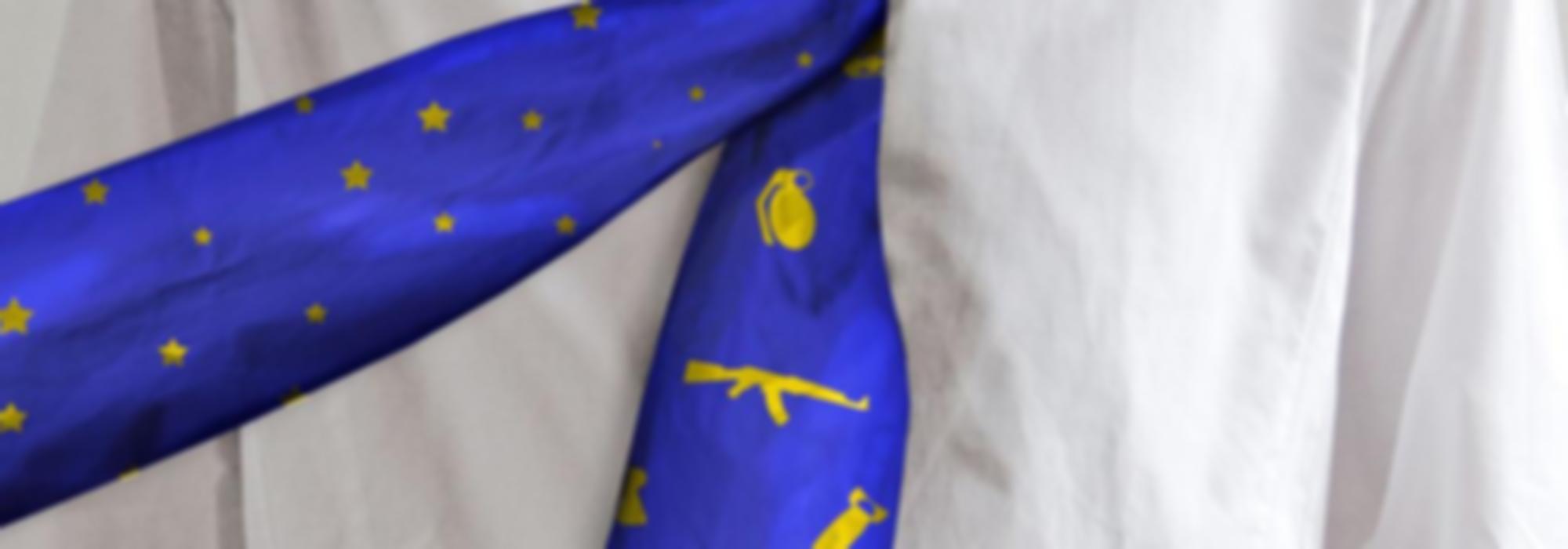 een man draagt een stropdas met europese sterren, met daaronder een tweede stropdas met wapens.