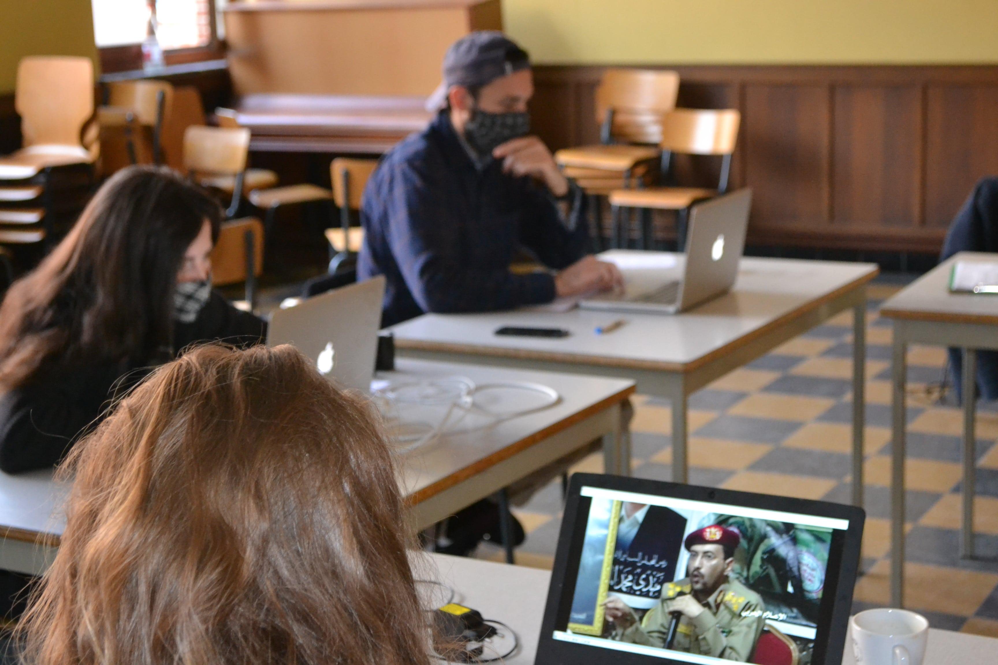 drie mensen achter een tafel met een computer op. Ze bekijken filmpjes voor het onderzoek.